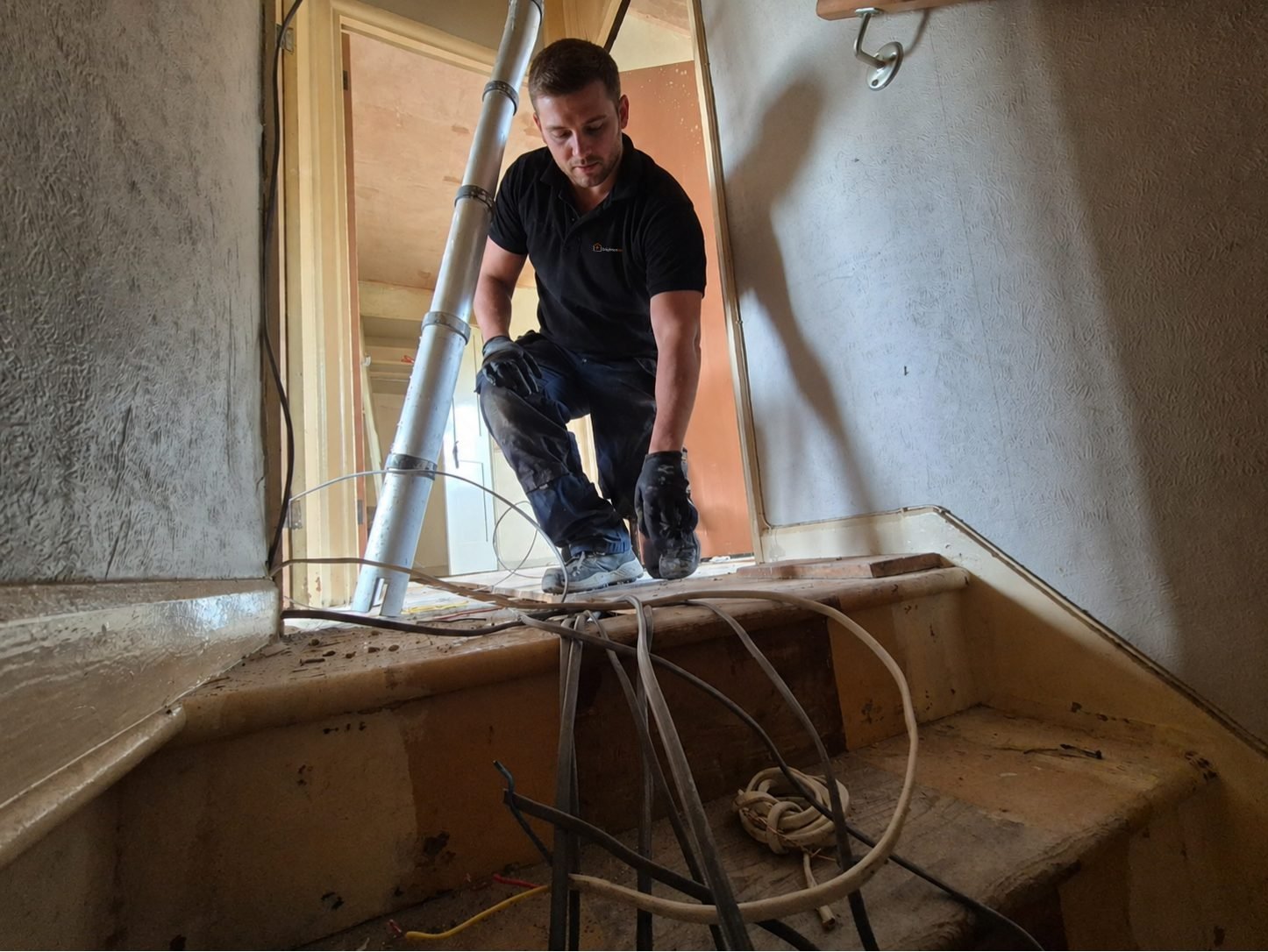 Electrician feeding cable through a stairwell during a Midhurst rewire