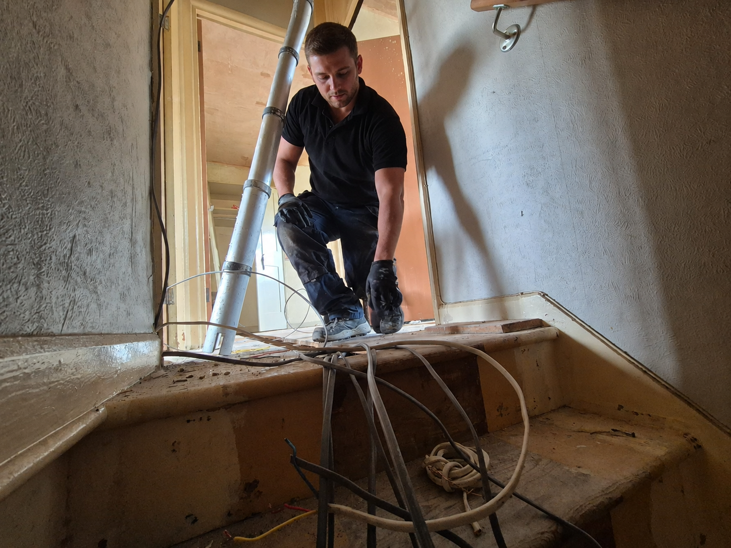 Electrician feeding cable through a stairwell